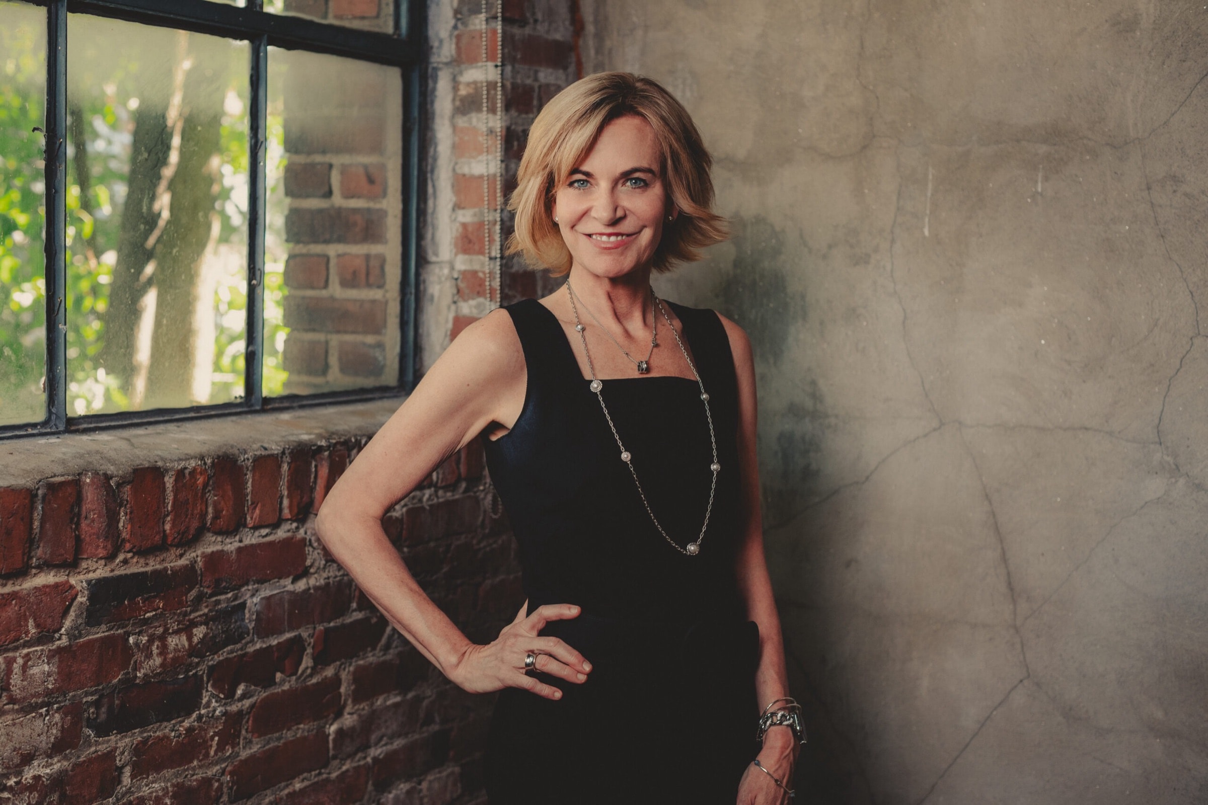 Dr. Tania Ferguson standing by a brick wall in her practice
